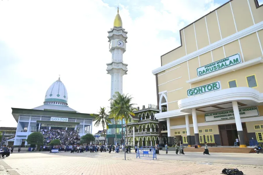Halaman Pondok Modern Darussalam Gontor: masjid berkubah, menara jam, dan Balai Pertemuan, dengan barisan santri di pelataran